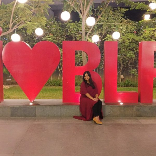 a woman sitting in front of a large red sign