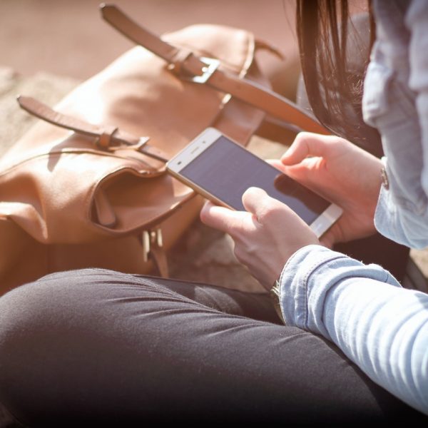 a person sitting on a rock looking at a cell phone