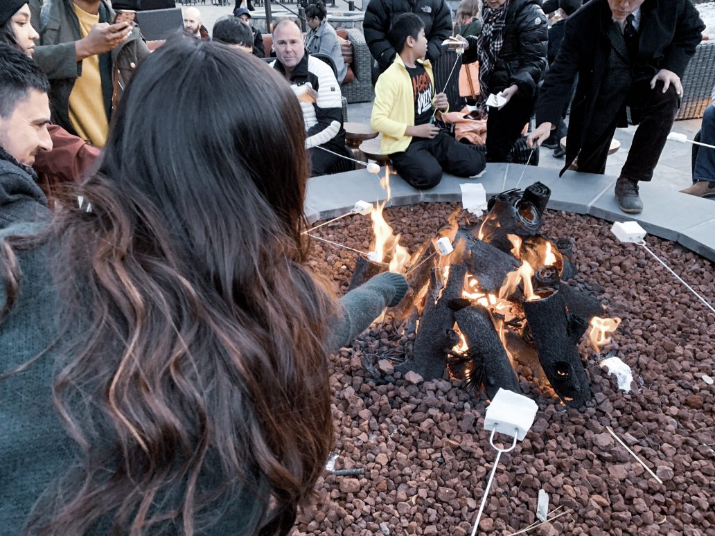a woman standing by a fire with people around it