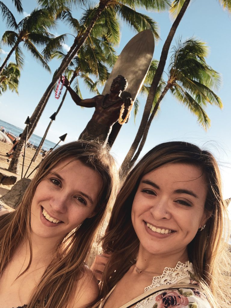 two women taking a selfie in front of a statue