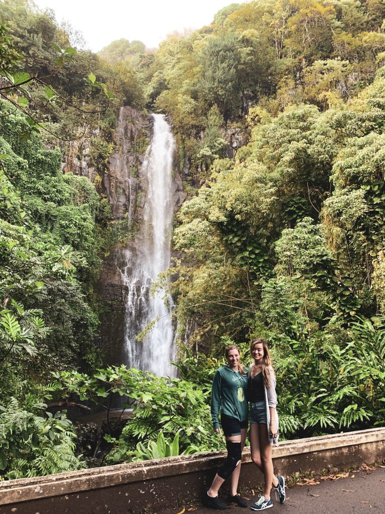 two women standing in front of a waterfall
