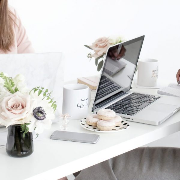 a woman sitting at a desk with a laptop and donuts