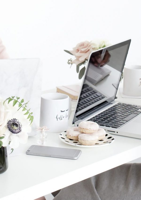 a woman sitting at a desk with a laptop and donuts