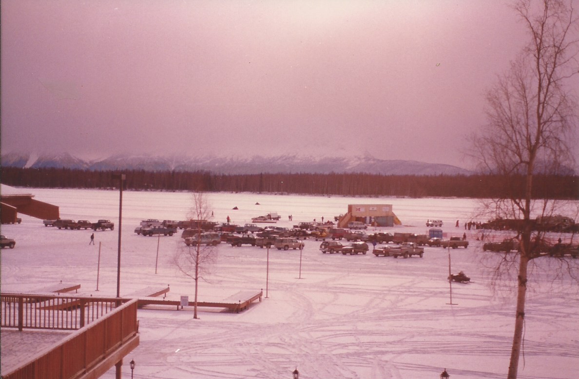 a large parking lot with cars and people in the snow