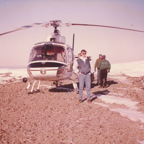 a group of people standing next to a helicopter