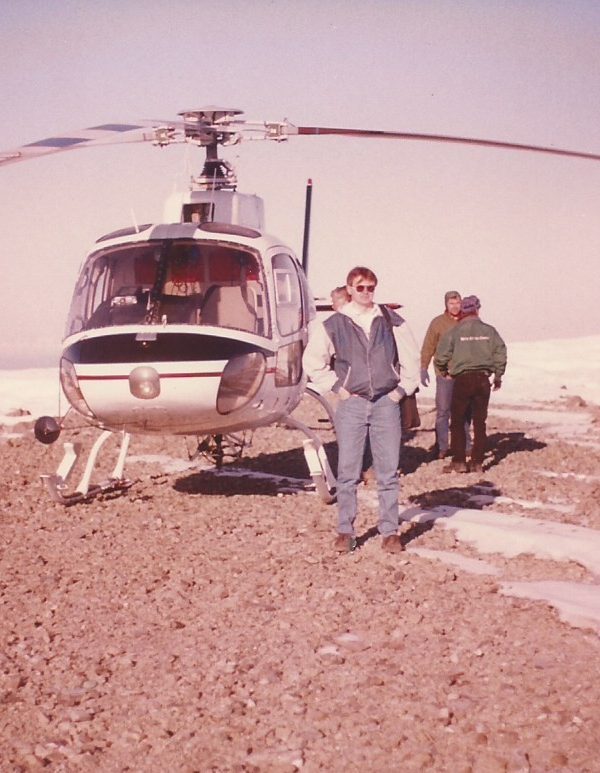 a group of people standing next to a helicopter