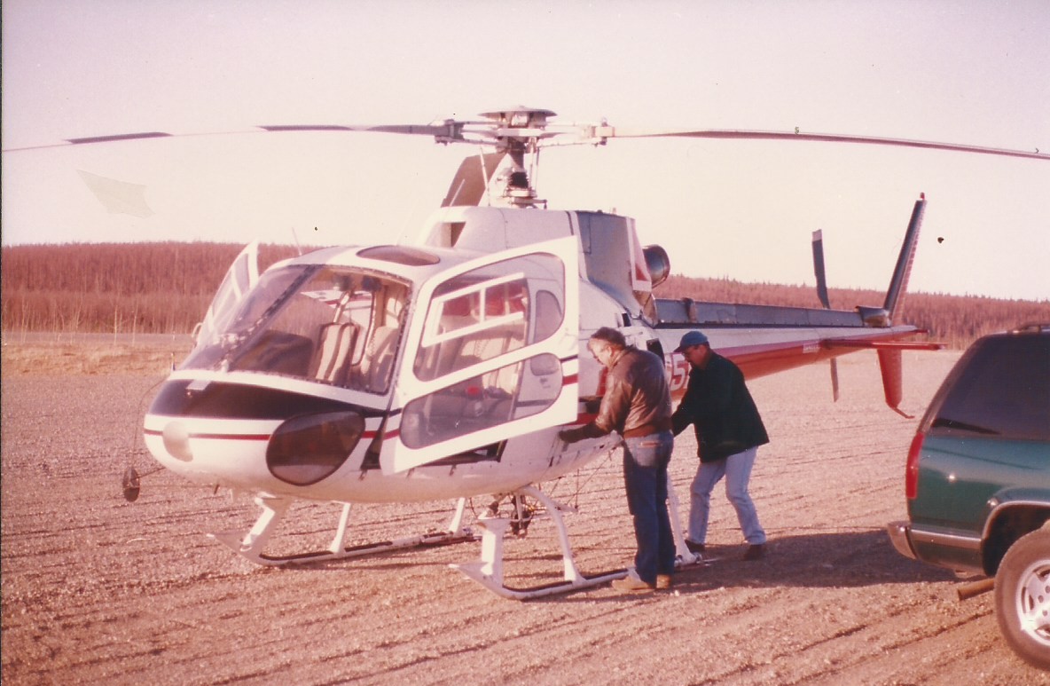 a group of men standing next to a helicopter