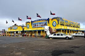 a yellow building with flags and a white car