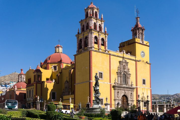 a yellow building with a clock tower and a statue