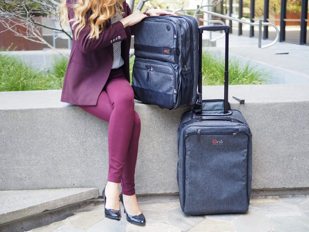 a woman sitting on a stone ledge with luggage