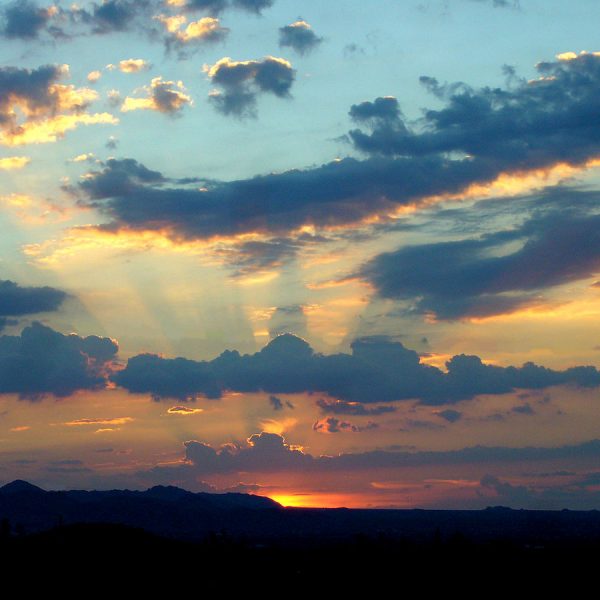 a sunset with clouds and mountains