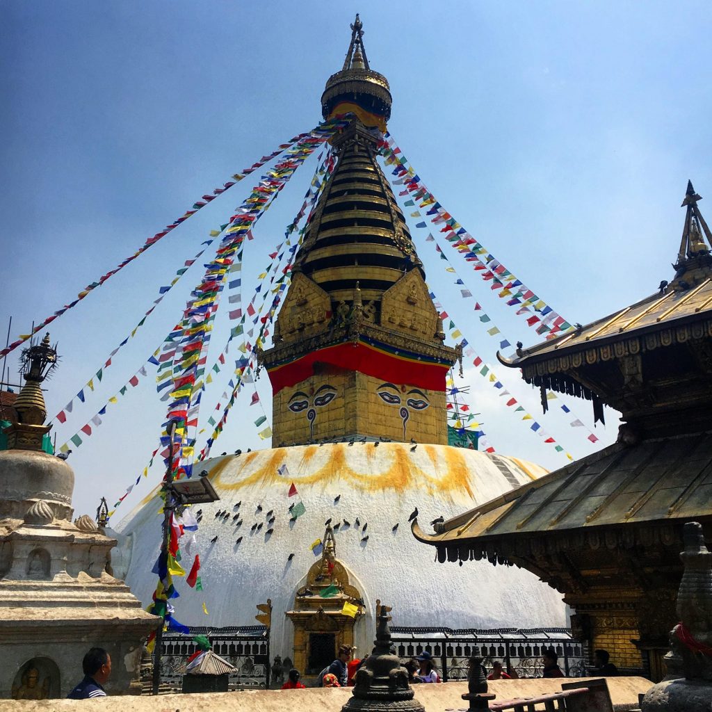 a large pagoda with colorful flags with Swayambhunath in the background