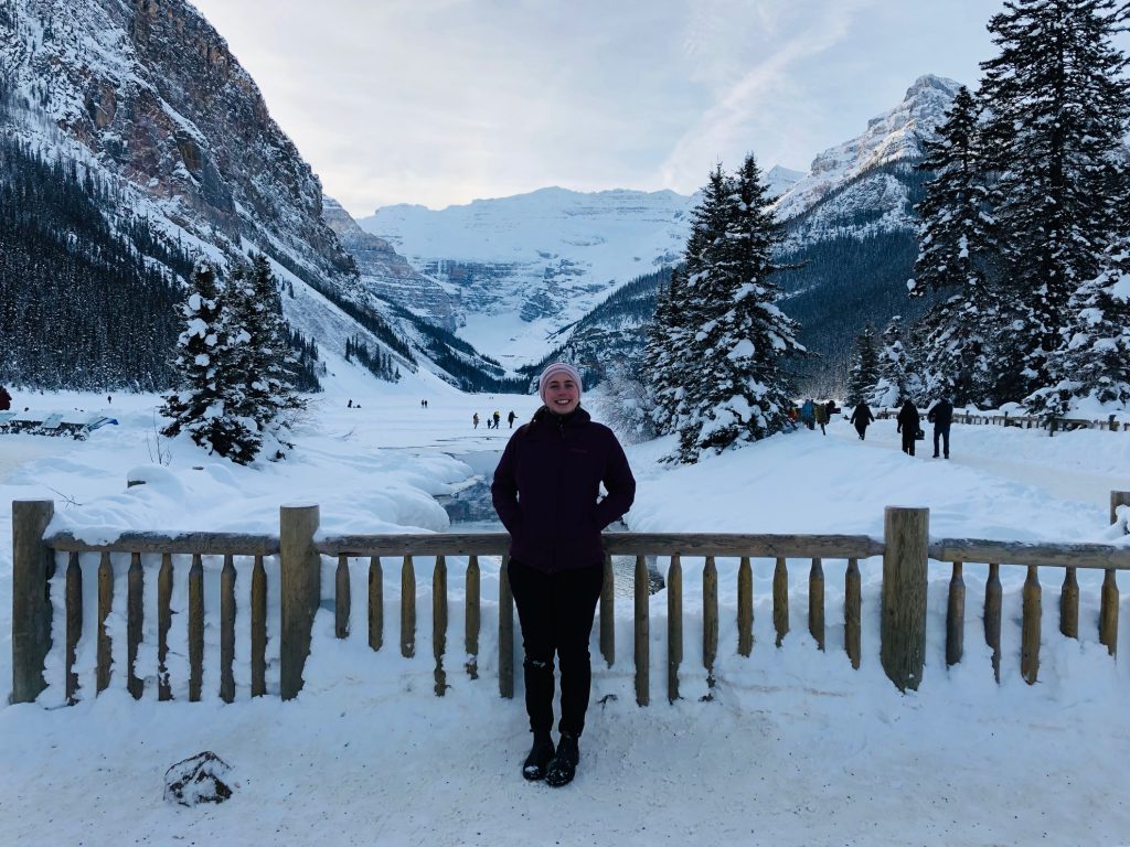 a woman standing in front of a fence in the snow