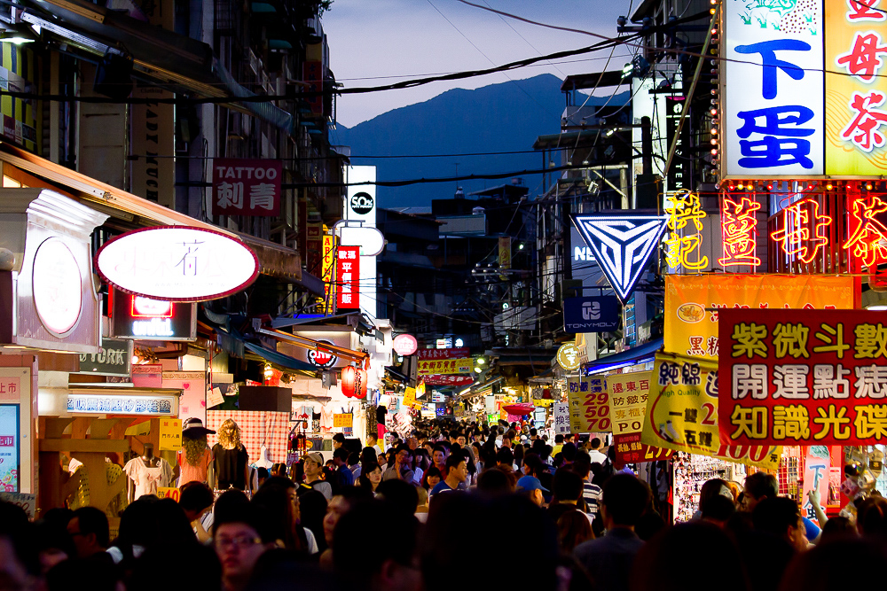 a crowd of people walking down a street with signs