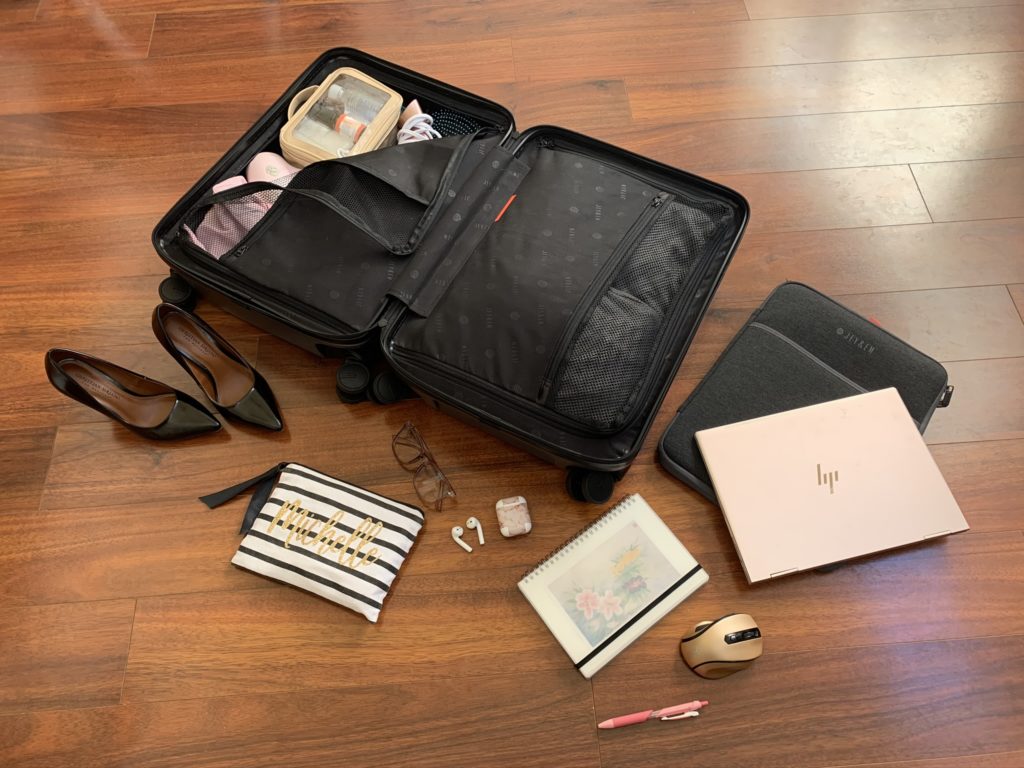 a suitcase with shoes and a laptop on a wood floor
