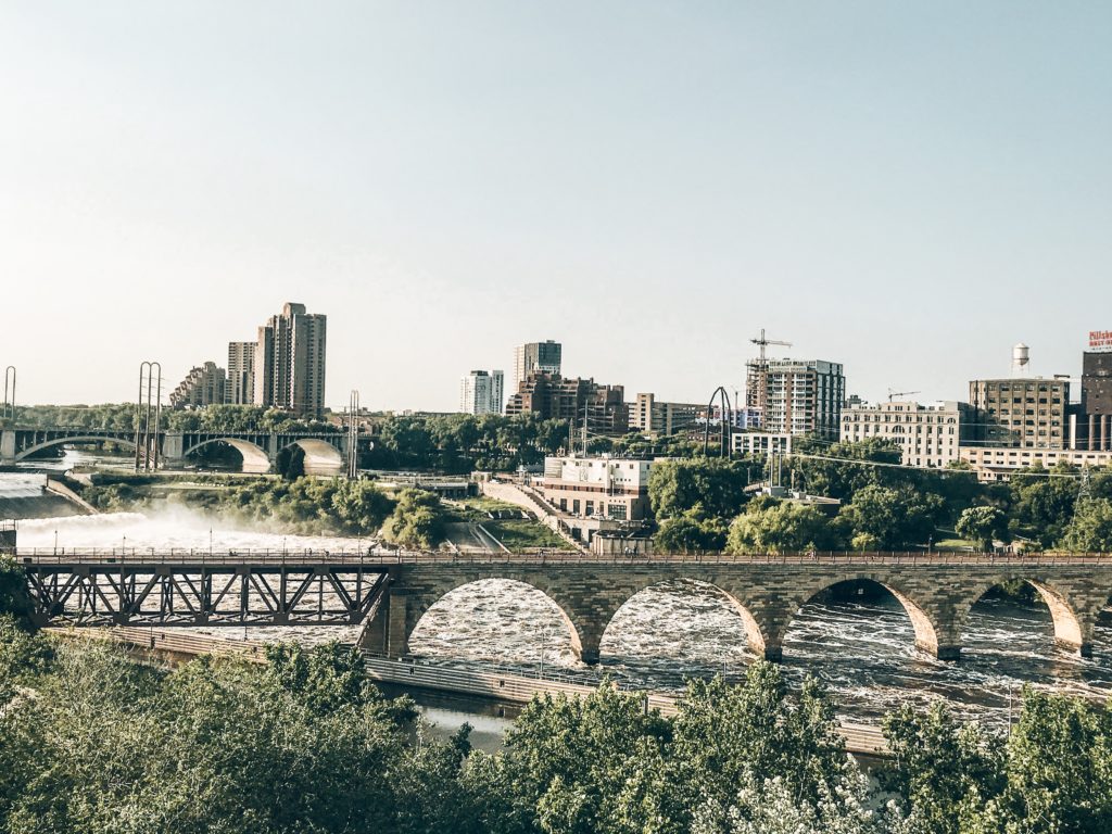 a bridge over a river with trees and buildings in the background