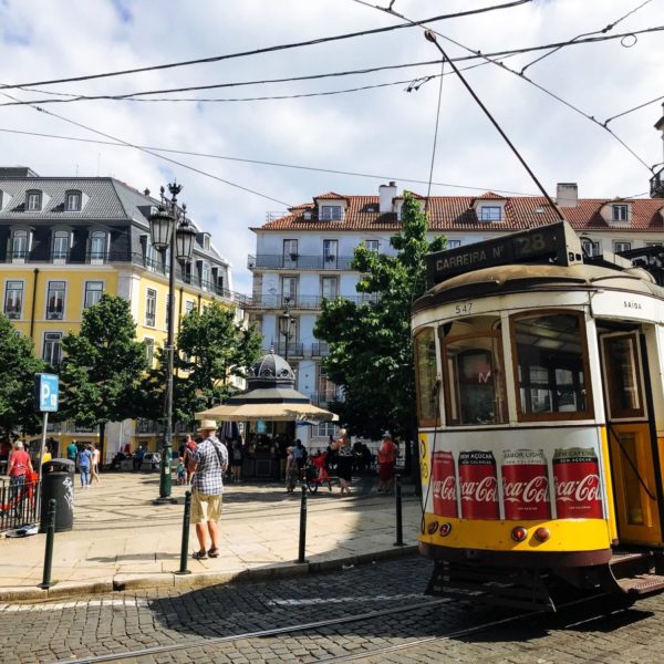 a yellow trolley on a street with people walking around