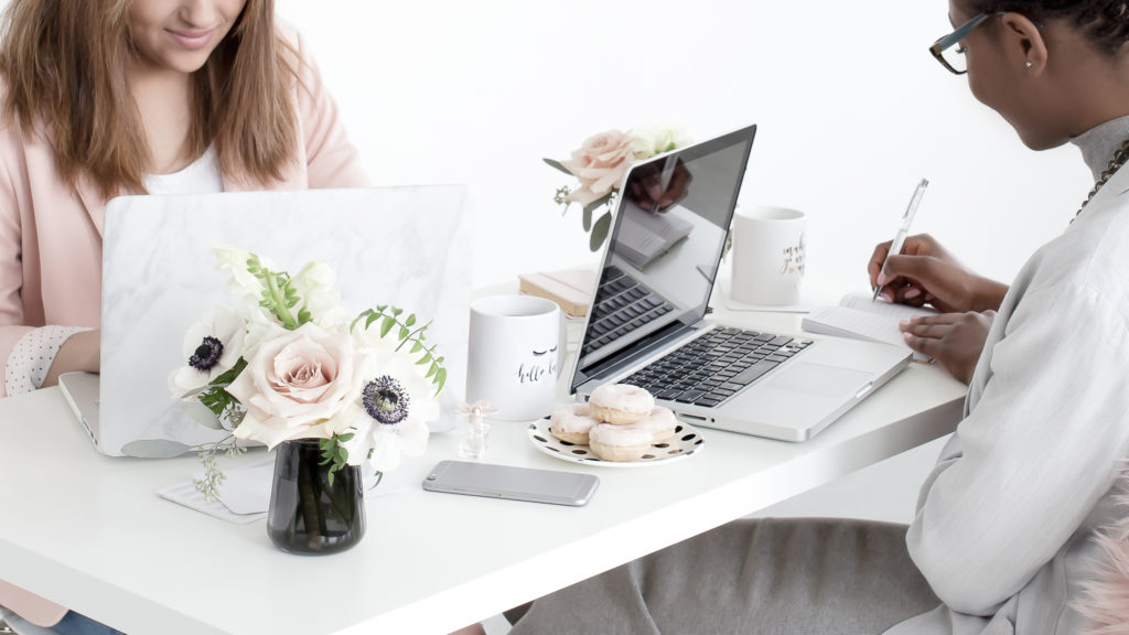 a woman sitting at a desk with a laptop and donuts