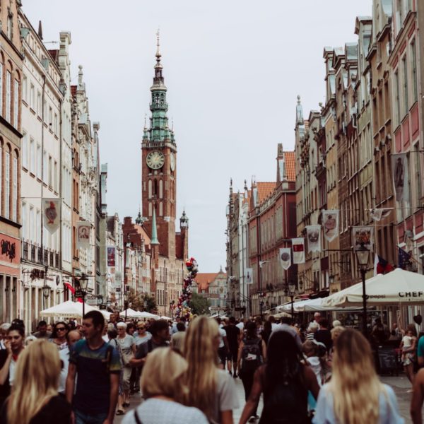 a group of people walking down a street with a clock tower