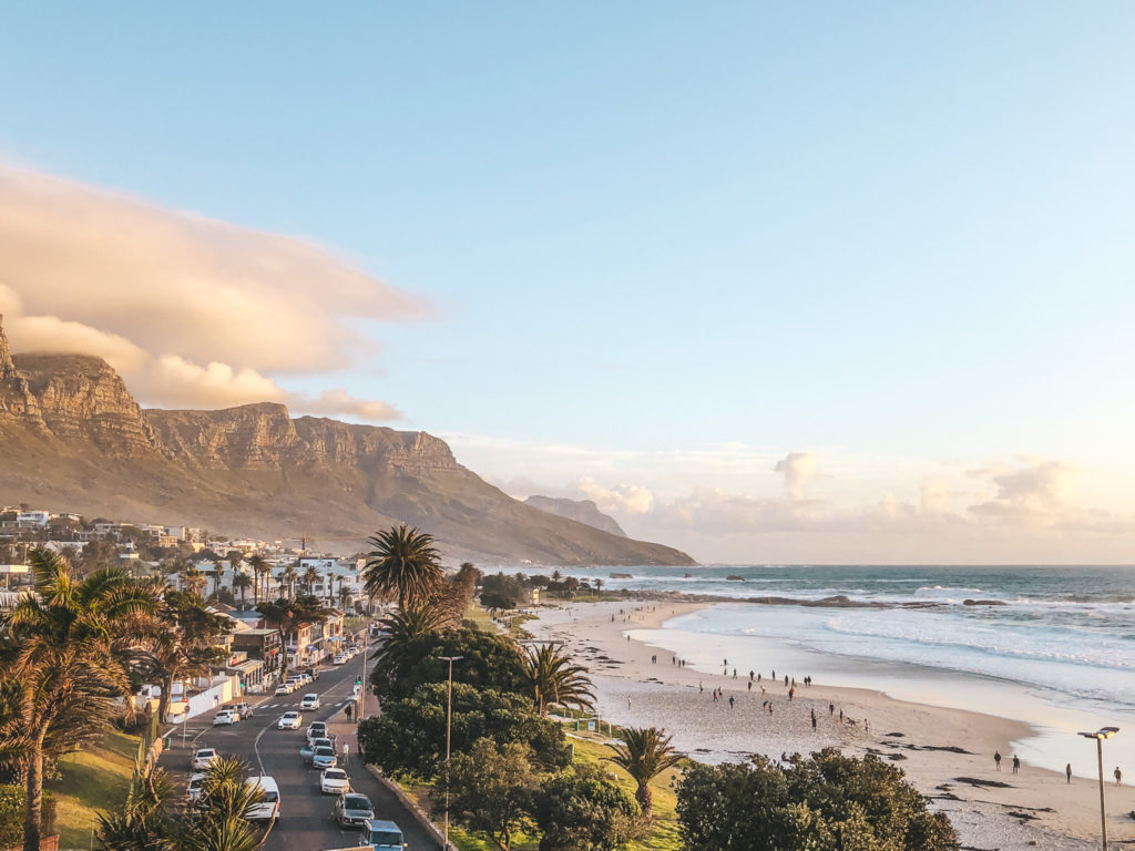 a beach with a city and mountains in the background