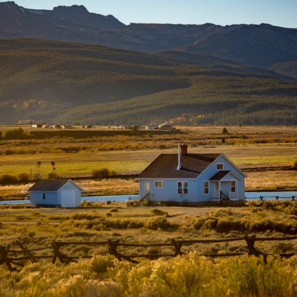 a house in a field with mountains in the background