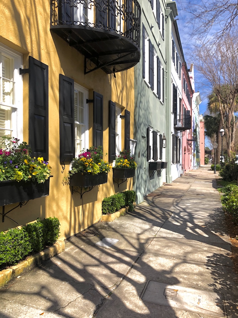 a sidewalk with colorful buildings and trees