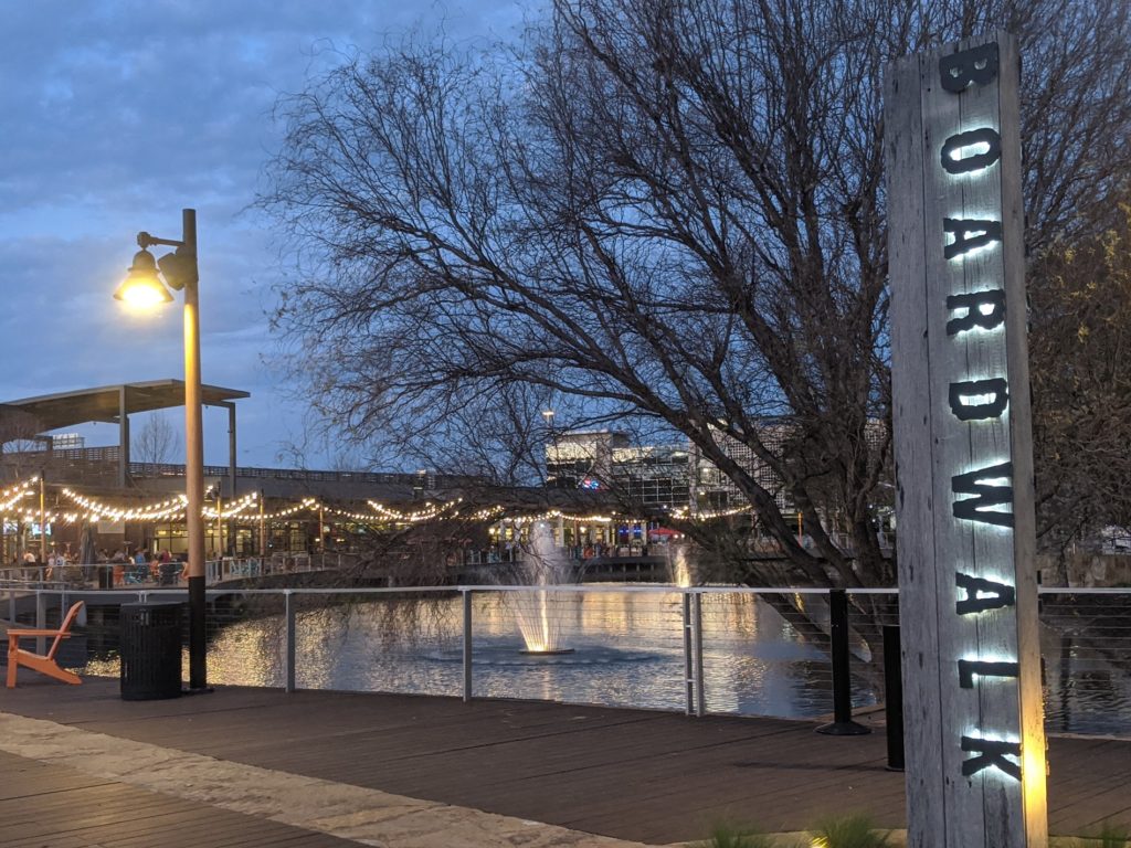 a sign with lights on it and a fountain in the middle of a pond