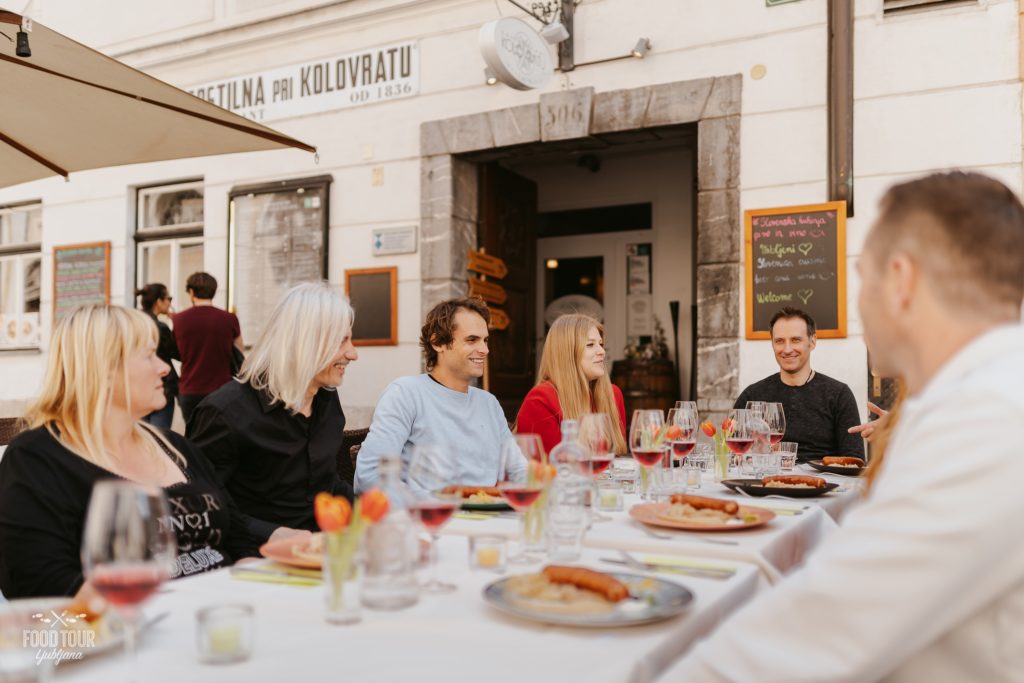 a group of people sitting at a table with food and drinks