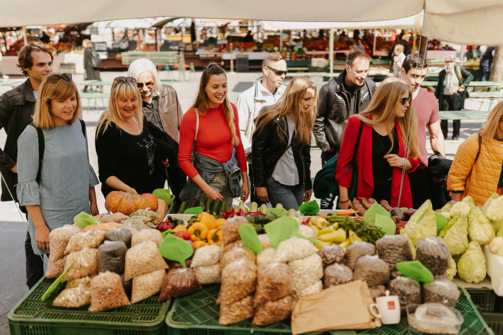 a group of people standing in front of a table full of produce