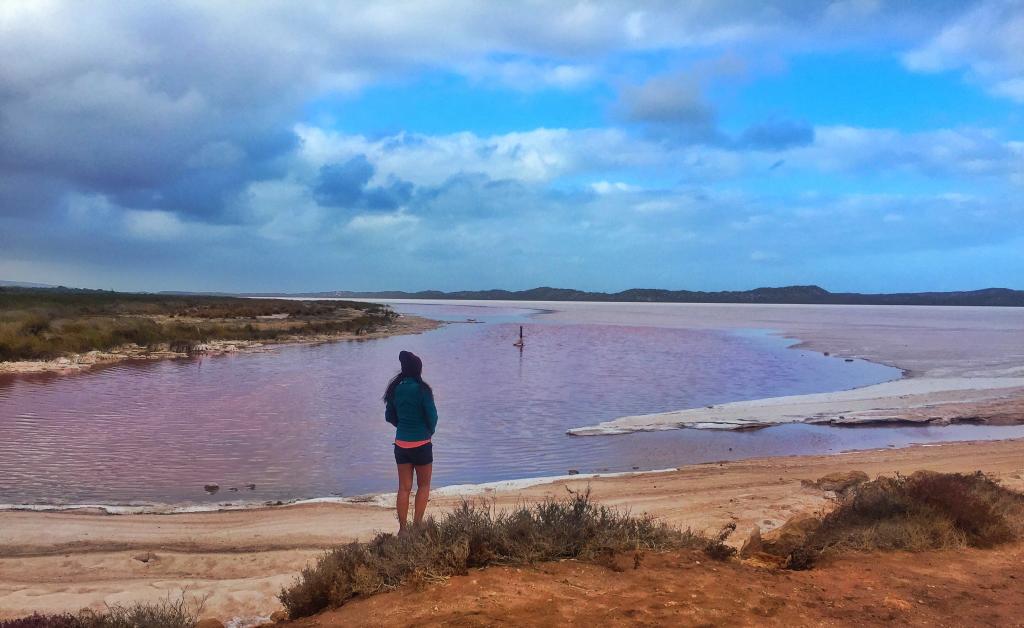 a woman standing on a beach looking at a body of water