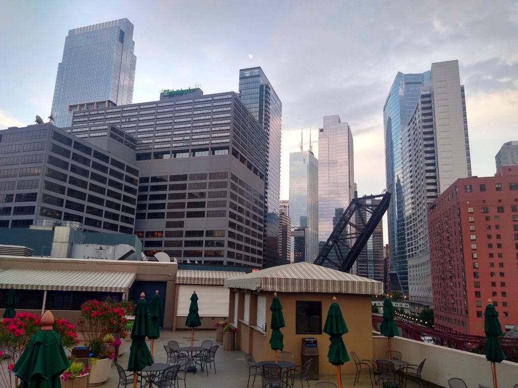 a rooftop patio with umbrellas and tables in a city