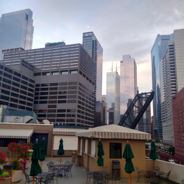 a rooftop patio with umbrellas and chairs in a city