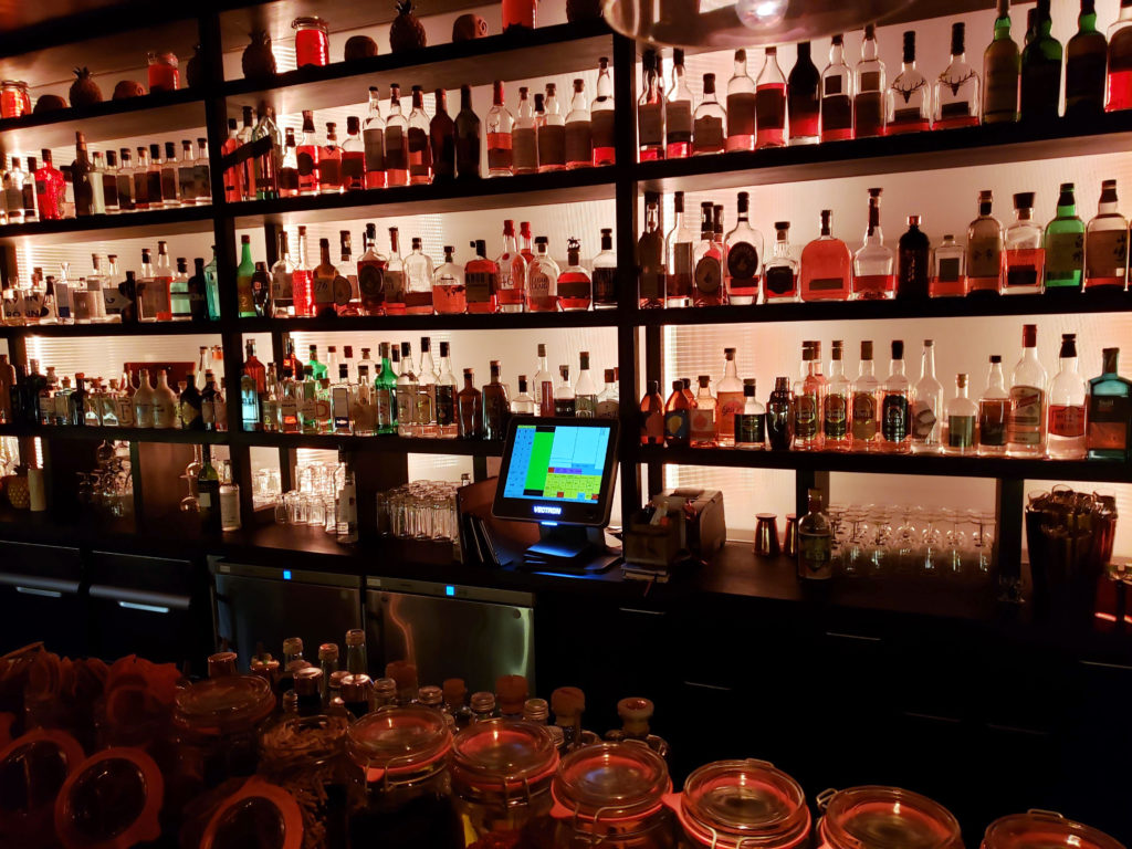 a bar with shelves of liquor and a computer
