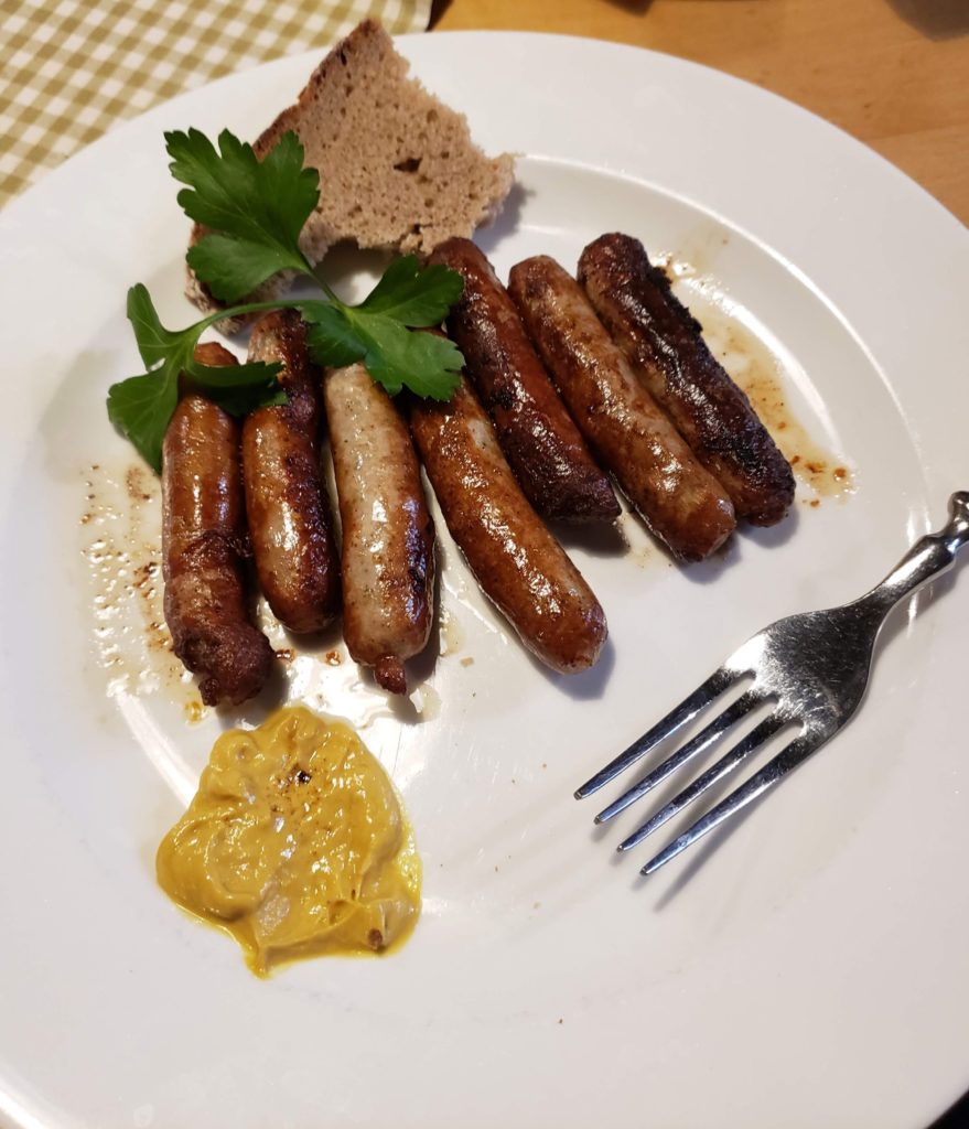 a plate of sausages and bread with mustard and a fork