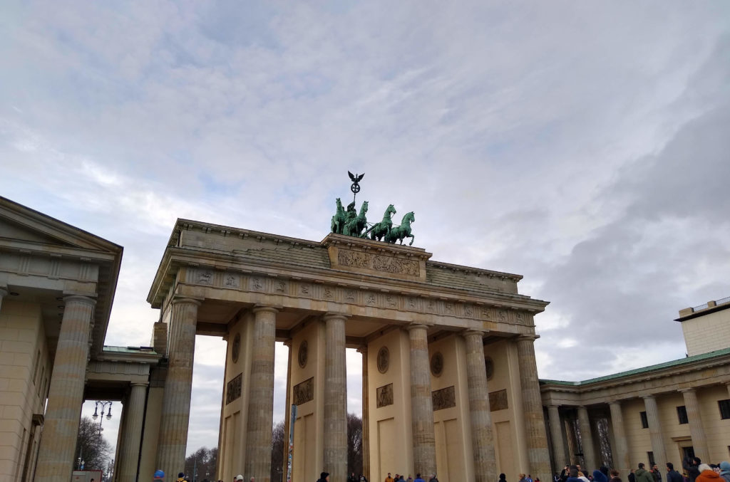 a stone structure with a statue of horses on top with Brandenburg Gate in the background