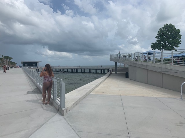 a woman standing on a concrete walkway overlooking a body of water