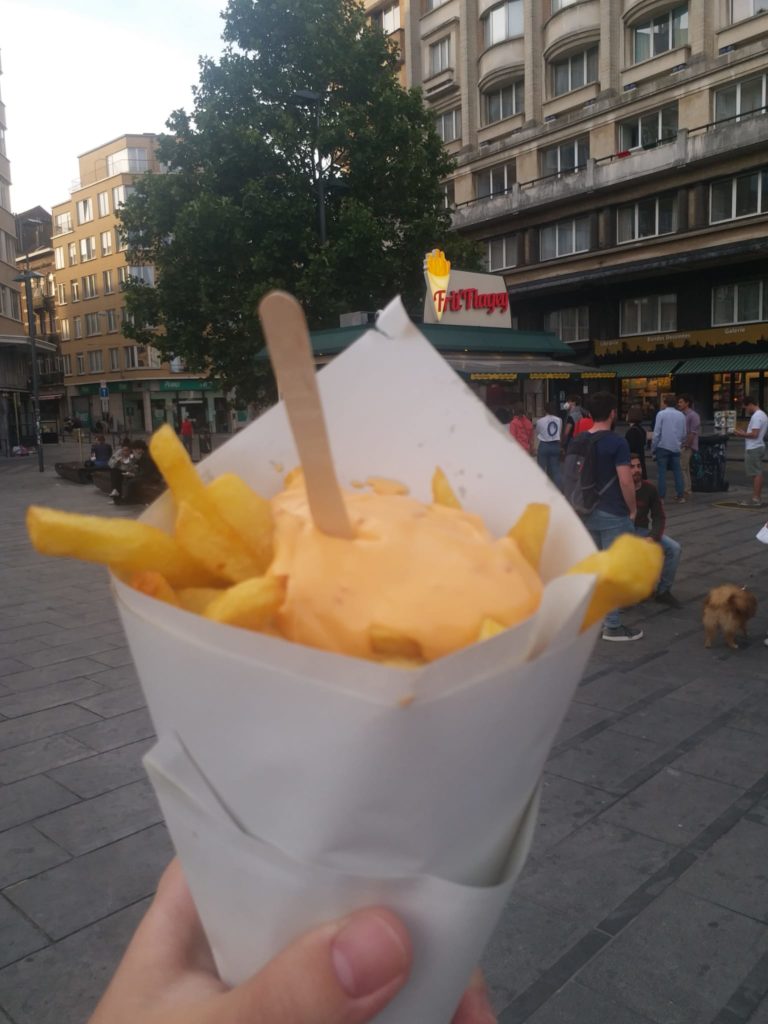 a hand holding a paper wrapper with food on it