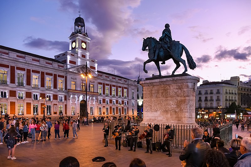 a group of people in front of a statue of a man on a horse