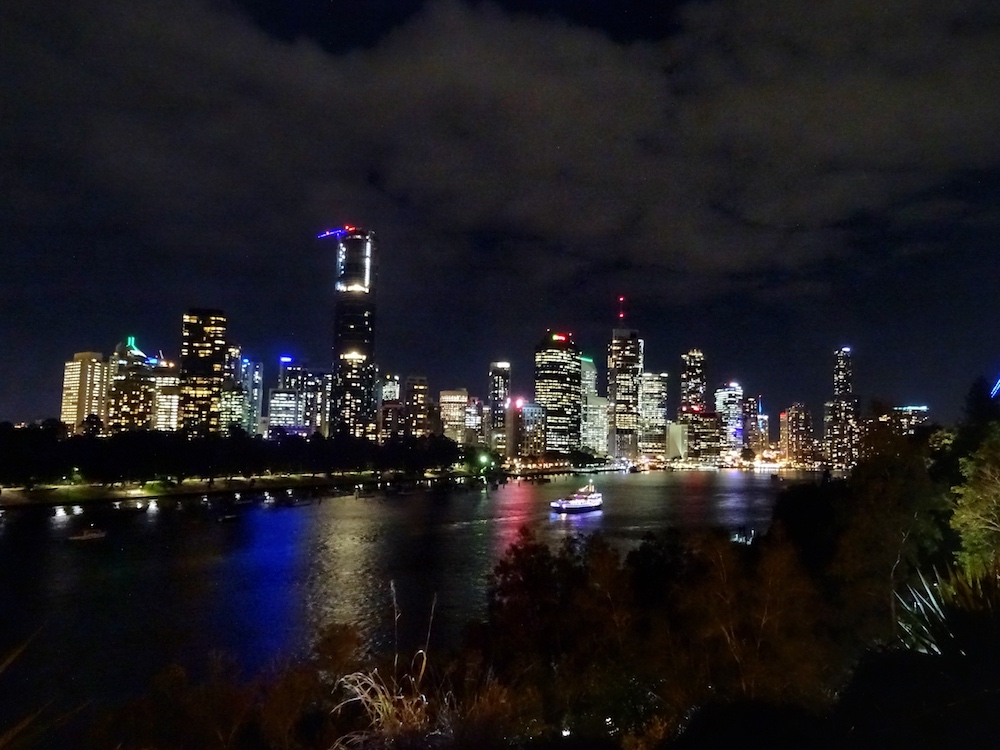 a city skyline at night with a river and a boat