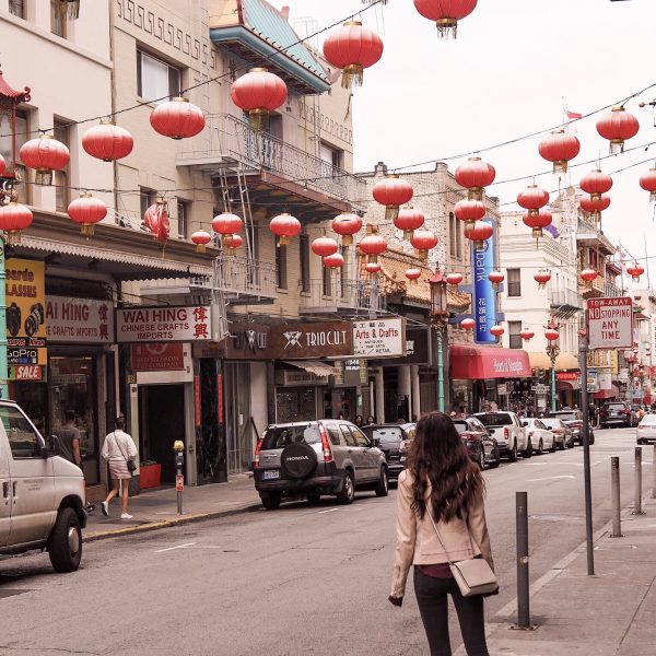 a woman walking down a street with red lanterns